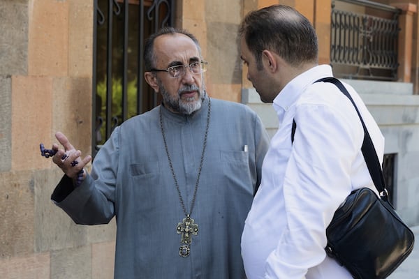 Mikael Ajapahyan, Archbishop of Gyumri and Shirak, left, speaks to a man as Armenian National Security Service officers arrive to arrest him, at Echmiadzin, the seat of the Armenian Apostolic Church outside Yerevan, Armenia, Friday, June 27, 2025. (Grigor Yepremyan, PAN Photo via AP)