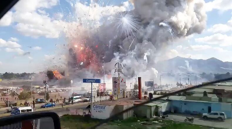This image made from video recorded from a passing car shows an explosion ripping through the San Pablito fireworks' market in Tultepec, Mexico, Tuesday, Dec. 20, 2016. Sirens wailed and a heavy scent of gunpowder lingered in the air after the afternoon blast at the market, where most of the fireworks stalls were completely leveled. According to the Mexico state prosecutor there are at least 26 dead. (Jose Luis Tolentino via AP)