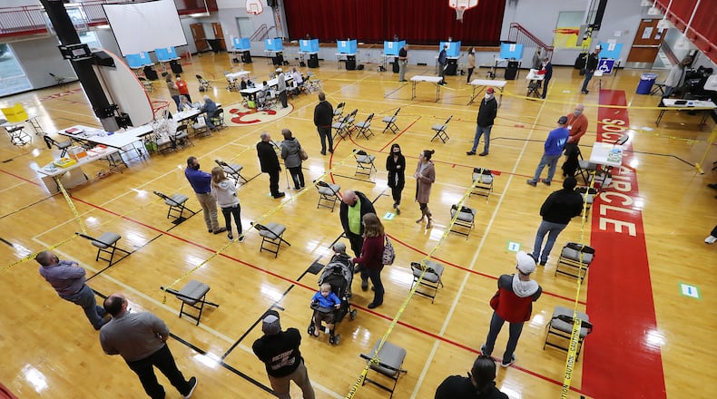 Voters socially distance Tuesday while waiting in line inside the gymnasium at Social Circle Middle School at to cast their votes in the U.S. Senate runoff election. Curtis Compton / Curtis.Compton@ajc.com”