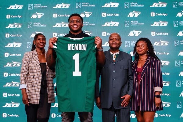 Offensive tackle Armand Membou, the New York Jets first round draft pick, seventh overall, poses with a jersey with his parents Suffo Membou, second from right, and Annie Melong, left, and sister during an NFL football press conference at team's training facility Friday, April 25, 2025, in Florham Park, N.J. (AP Photo/Kena Betancur)