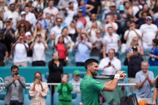 Novak Djokovic, of Serbia, mimes playing a violin with his racket as he celebrates winning his semifinal match against Grigor Dimitrov, of Bulgaria, at the Miami Open tennis tournament, Friday, March 28, 2025, in Miami Gardens, Fla. (AP Photo/Rebecca Blackwell)