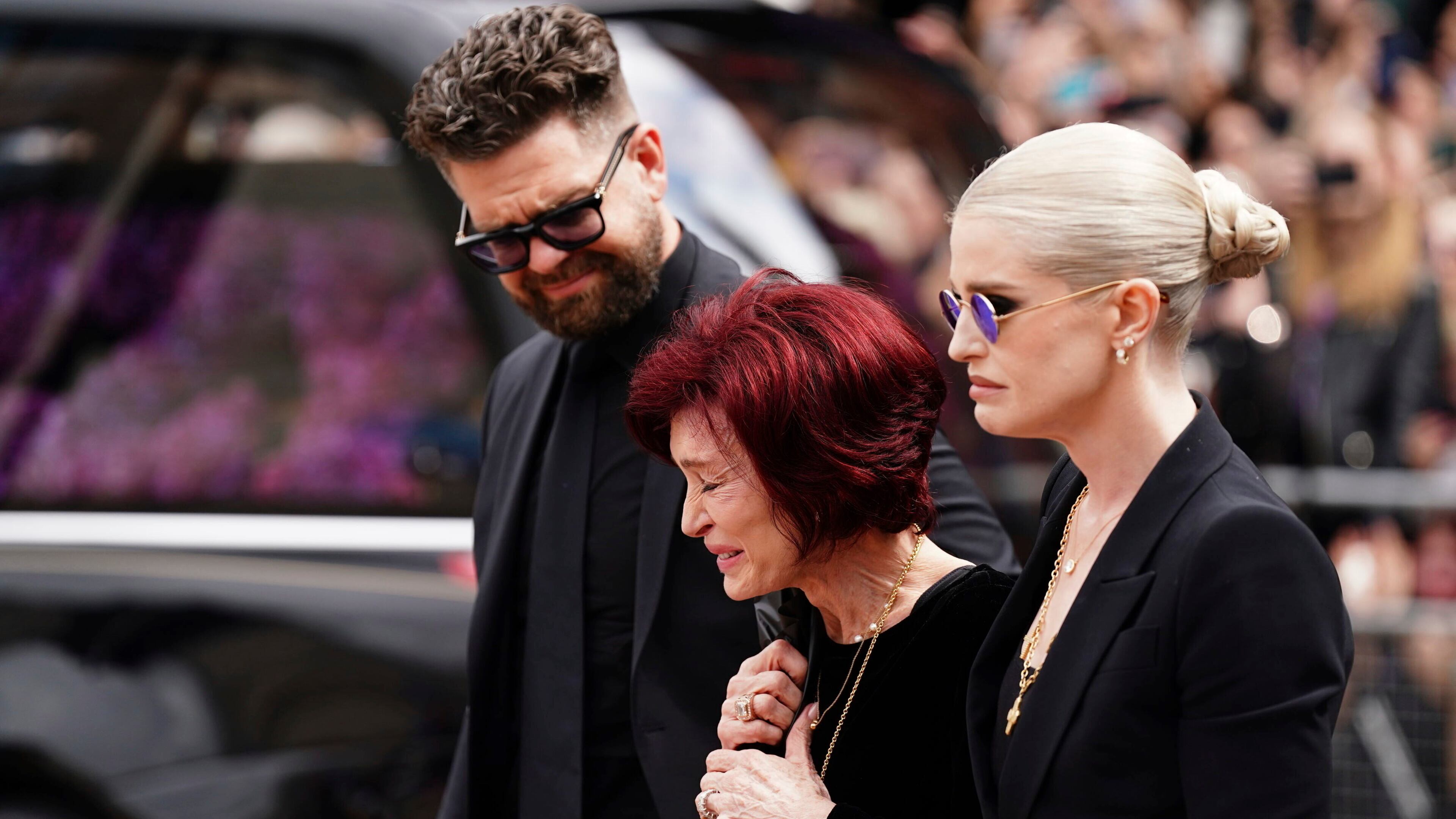 The family of Ozzy Osbourne from left, Jack Osbourne, Sharon Osbourne and Kelly Osbourne lay flowers and view the flowers left at the Black Sabbath Bridge bench on Broad Street in memory of Black Sabbath frontman Ozzy Osbourne ahead of the funeral procession, in Birmingham, England, Wednesday July 30, 2025. (Jacob King/PA via AP)