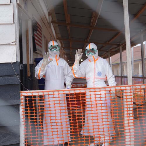 Health workers in protective gear wave inside an Ebola treatment centre in Bunia, Congo, Monday, Aug. 10, 2026. (AP Photo/Dieudonne Dirole)