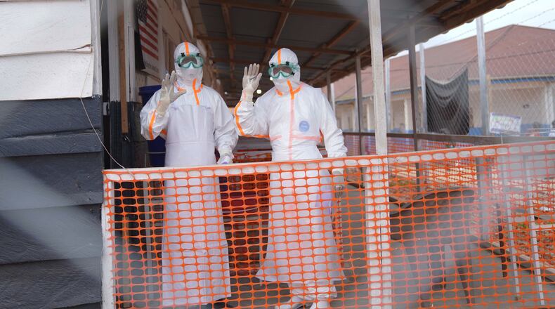 Health workers in protective gear wave inside an Ebola treatment centre in Bunia, Congo, Monday, Aug. 10, 2026. (AP Photo/Dieudonne Dirole)