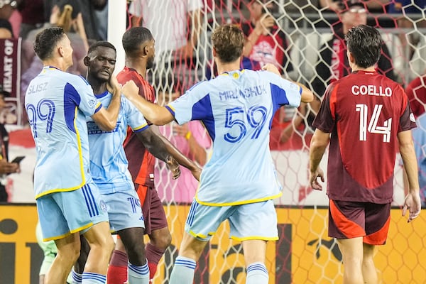 Atlanta United's Emmanuel Latte Lath, second from left, is congratulated Bartosz Slisz (99) and Aleksey Miranchuk (59) after converting the tying penalty kick as Toronto FC's Alonso Coello (14) looks on during second-half MLS soccer match action in Toronto, Saturday, July 12, 2025. (Chris Young/The Canadian Press via AP)