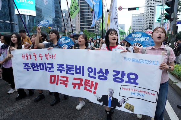 Supporters of the South Korean Confederation of Trade Unions march during a rally against the government's labor policy and U.S. President Donald Trump's tariffs policy on South Korea, in Seoul, South Korea, Saturday, July 19, 2025. The banner reads "We Condemn U.S. for forcing the the costs of station U.S. troops in South Korea!."(AP Photo/Ahn Young-joon)