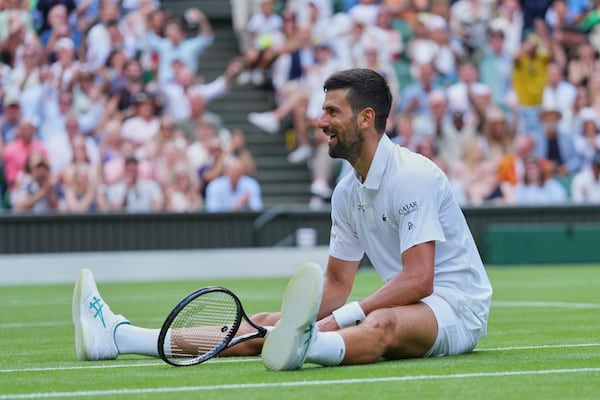 Novak Djokovic of Serbia sits on the grass after diving to return to Miomir Kecmanovic of Serbia during a third round men's singles match at the Wimbledon Tennis Championships in London, Saturday, July 5, 2025. (AP Photo/Kirsty Wigglesworth)