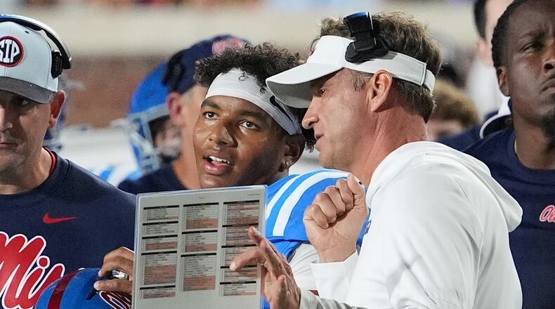 FILE - Mississippi head coach Lane Kiffin, center right, confers with quarterback Trinidad Chambliss, center left, during an NCAA college football game against Florida, Nov. 15, 2025, in Oxford, Miss. (AP Photo/Rogelio V. Solis, File)