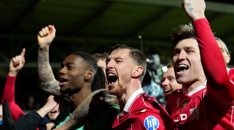 Wrexham's goalkeeper Arthur Okonkwo, left, celebrates with teammates after a penalty shootout at the end of the English FA Cup third round soccer match between Wrexham and Nottingham Forest in Wrexham, Wales, Friday, Jan. 9, 2026. (AP Photo/Jon Super)