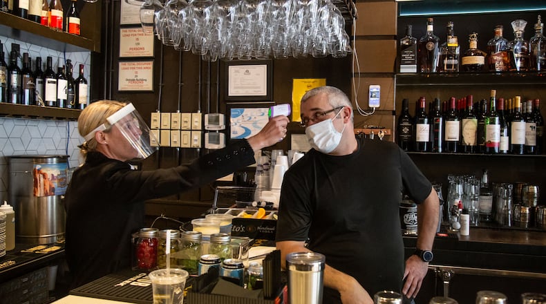 1920 Tavern Owner Jenna Aronowitz takes the temperature of bartender Shane Goode before the Roswell restaurant opens for sit down meals Monday, April 27, 2020. STEVE SCHAEFER / SPECIAL TO THE AJC