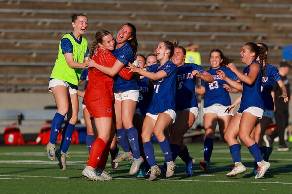 Jefferson goalkeeper Isabell Ikirt (0, in red) celebrates with teammates after she made the game saving stop as Jefferson defeated Oconee County 4-3 in an extra time penalty kick shootout during the GHSA 3A girls soccer state championship at Duluth High School, Tuesday, May 12, 2026, in Duluth, Ga. (Jason Getz/AJC)