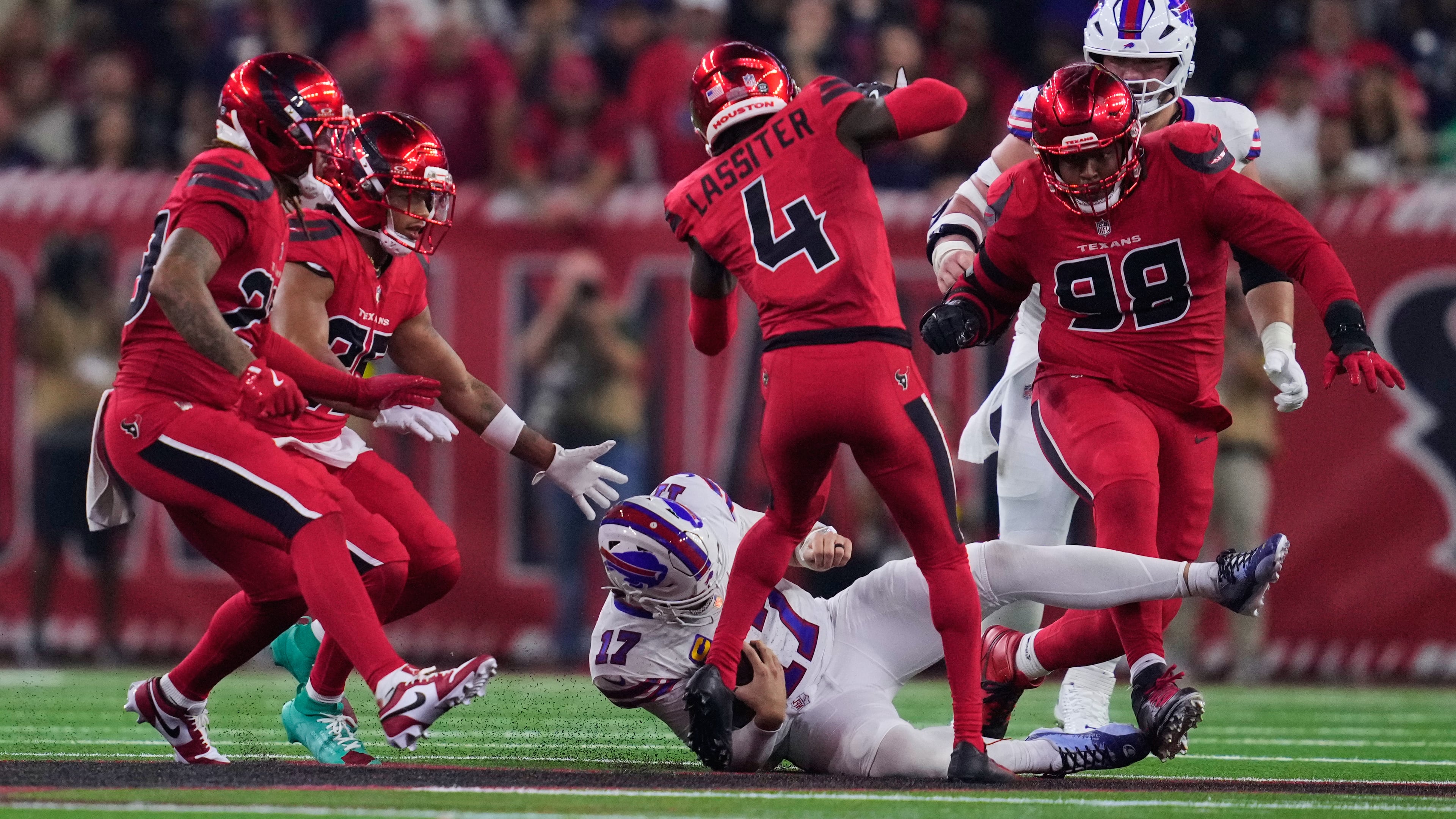Buffalo Bills quarterback Josh Allen (17) slides to a stop under pressure from Houston Texans' Kamari Lassiter (4), Tim Settle Jr. (98) and others in the second half of an NFL football game Thursday, Nov. 20, 2025, in Houston. (AP Photo/Ashley Landis)