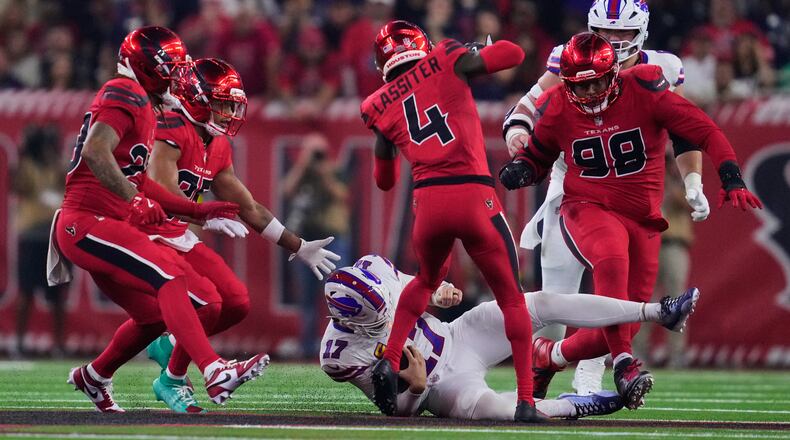 Buffalo Bills quarterback Josh Allen (17) slides to a stop under pressure from Houston Texans' Kamari Lassiter (4), Tim Settle Jr. (98) and others in the second half of an NFL football game Thursday, Nov. 20, 2025, in Houston. (AP Photo/Ashley Landis)
