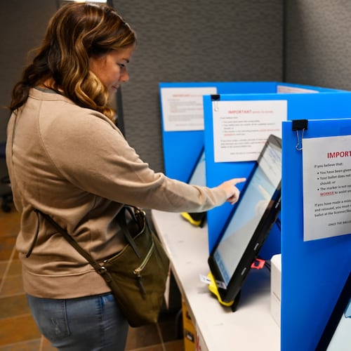 FILE- Courtney Parker votes on a new voting machine, in Dallas, Ga., Nov. 5, 2019. (AP Photo/Mike Stewart, File)