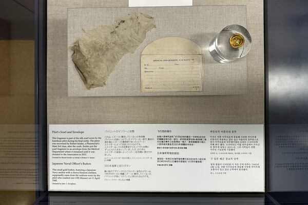 A fragment of a silk scarf and a button worn by the kamikaze pilot of a Japanese zero plane that rammed into the USS Missouri during the Battle of Okinawa is on display at the Battleship Missouri Memorial in Pearl Harbor on April 3, 2025. (AP Photo/Audrey McAvoy)