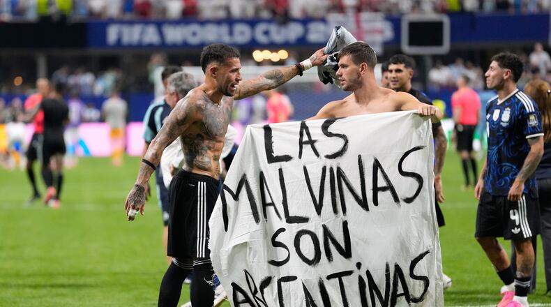 Argentina's Giovani Lo Celso holds a banner with the words "The Malvinas are Argentine", referring to the Falkland Islands, while teammate Argentina's Nicolas Otamendi gestures to him, at the end of the World Cup semifinal soccer match between England and Argentina in Atlanta, Wednesday, July 15, 2026. (AP Photo/Rebecca Blackwell)