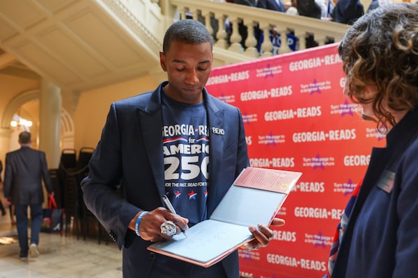 Author and former football player Malcolm Mitchell signs a copy of his book "Hey Georgia" following a Georgia Reads literacy rally at the Capitol in Atlanta on Tuesday, March 3, 2026. (Arvin Temkar/AJC)