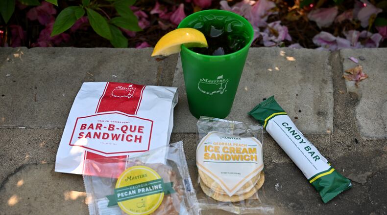 Augusta National Golf Club’s food items include a pork bar-b-que sandwich (clockwise from left), ice tea, a Masters candy bar, a Georgia peach ice cream sandwich and a Georgia pecan praline. Augusta National is famous for its affordable, iconic concession menu. (Hyosub Shin/AJC)