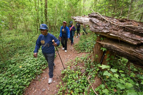 Nature Gurlz members Barbara Hardeman (left) and Sherry B. Williams, lead the Nature Gurlz past a downed tree along the trail at Cascade Springs Nature Preserve on April 22, 2025, in Atlanta. (Jason Getz/AJC)