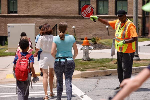 Watching school crossing guard Larry McCrary manage the traffic at the intersection of Talley and New streets is like watching a maestro conduct an orchestra. His third year working with City Schools of Decatur, McCrary is a familiar and welcome face in the neighborhood. (Natrice Miller/AJC)