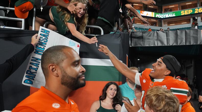 Miami quarterback Darian Mensah, right, signs autographs after an NCAA college football game against Florida A&M, Thursday, Sept. 10, 2026, in Miami Gardens, Fla. (AP Photo/Lynne Sladky)