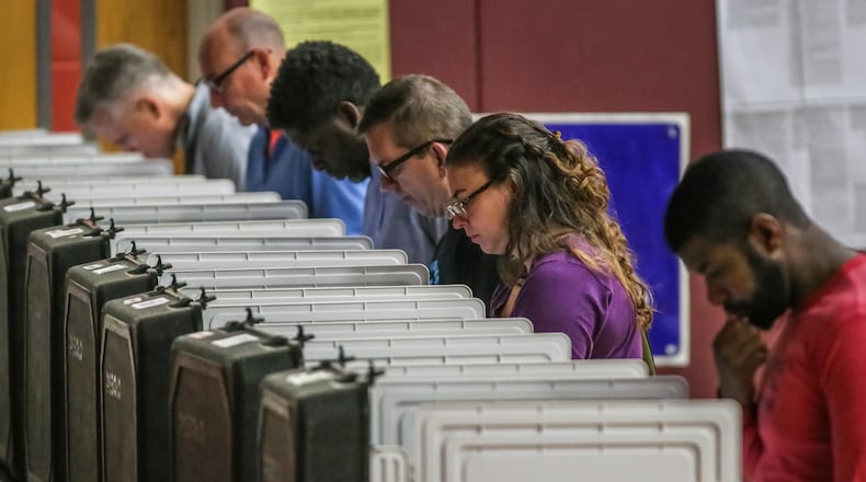 In this file photo, voters ponder May primary ballots at Henry W. Grady High School in Atlanta.  JOHN SPINK/JSPINK@AJC.COM