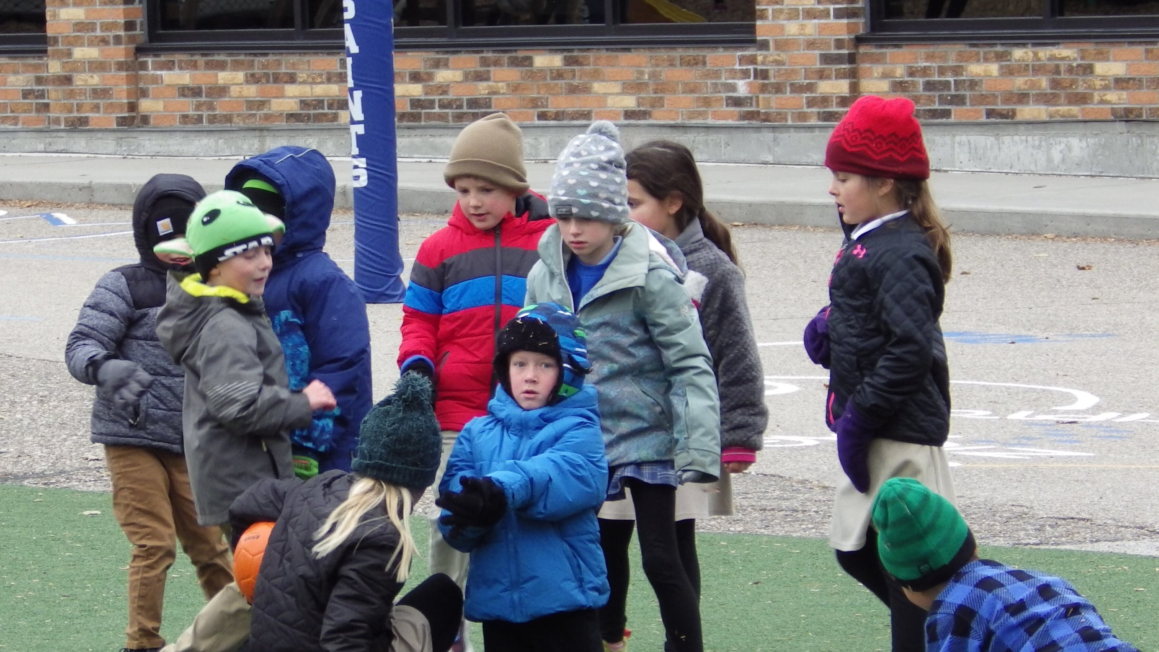 Children wearing coats, hats and gloves play with a ball Friday, Nov. 7, 2025, at St. Mary's Elementary School in Bismarck, N.D. (AP Photo/Jack Dura)