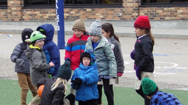 Children wearing coats, hats and gloves play with a ball Friday, Nov. 7, 2025, at St. Mary's Elementary School in Bismarck, N.D. (AP Photo/Jack Dura)