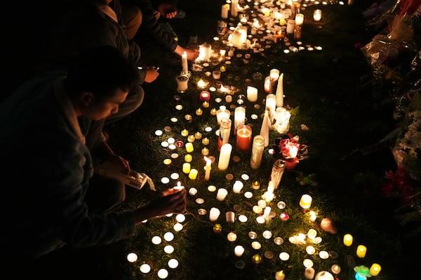 Wendell Gomez, left, places a candle at a memorial for victims after a vehicle drove into a crowd during a Filipino heritage festival in Vancouver, British Columbia, Monday, April 28, 2025. (AP Photo/Lindsey Wasson)