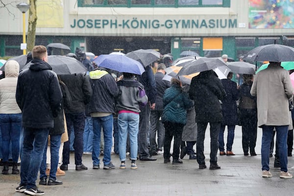 People standing in the rain during a memorial ceremony at the schoolyard of the Joseph-Koenig high school in Haltern, Germany, ten years after 16 pupils and two teachers of the school died in the Germanwings crash in the French Alps, Monday, March 24, 2025. (AP Photo/Martin Meissner)