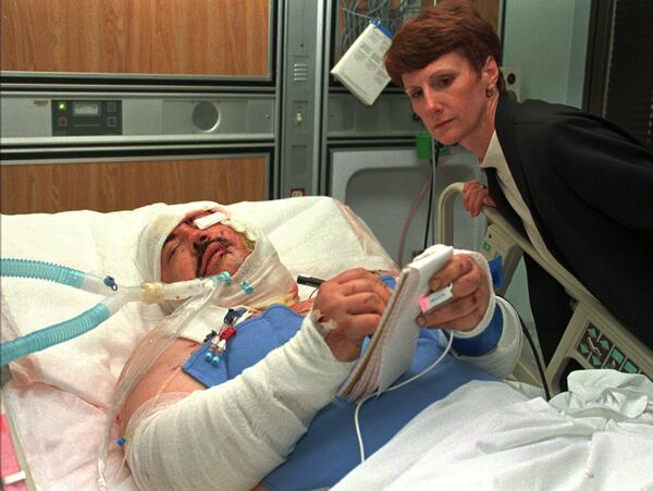 FILE - Randy Ledger, who was severely injured by the bomb blast at the Alfred P. Murrah Federal Building, writes a note from his bed in the intensive care unit of Presbyterian Hospital in Oklahoma City on April 20, 1995, as his sister, Linda Halford, watches. (AP Photo/Pat Sullivan, File)