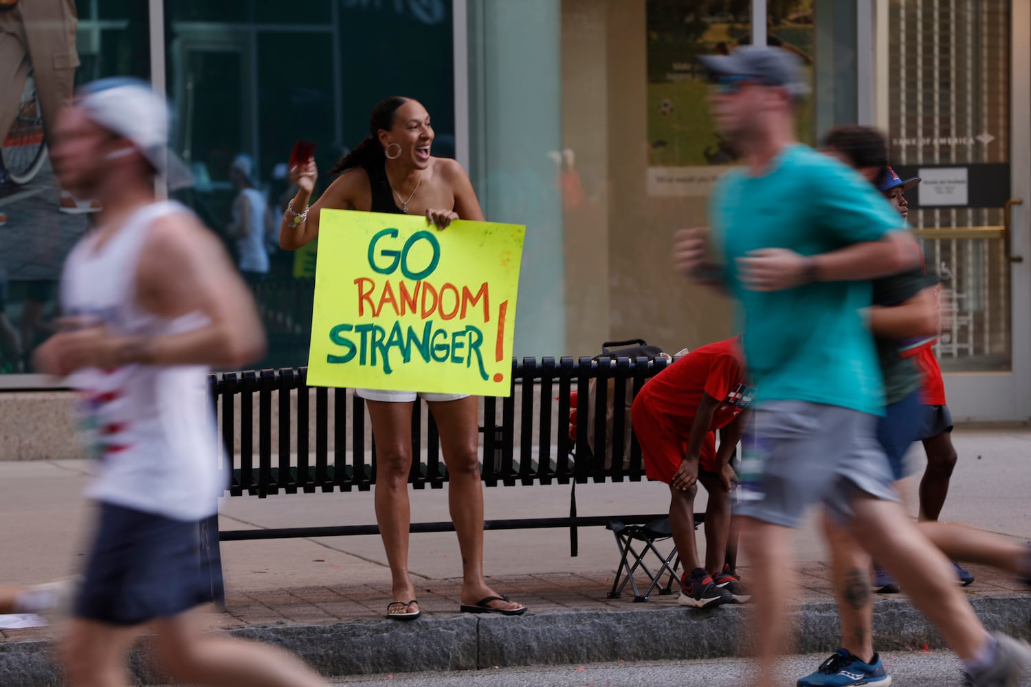 A woman cheers on runners near 11th Street at  the 56th running of the Atlanta Journal-Constitution Peachtree Road Race in Atlanta on Friday, July 4, 2025.   (Natrice Miller / AJC)