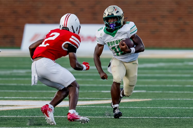 Buford's AJ Granville (right) runs while being defending by Gainesville's JaMarcus Sims during the second half Saturday, Aug. 22, 2026, in Buford. The Class 7A No. 1 Wolves beat the 6A No. 2 Red Elephants 39-19. (Erik S. Lesser for the AJC)