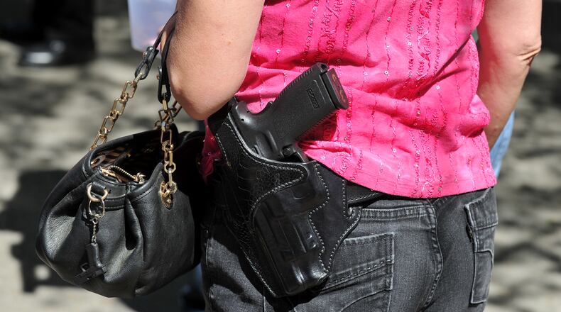Cindy Wheeler carries her gun while handing out buttons at a House Bill 60 signing event in Ellijay, Ga., on April 23, 2014. The gun bill, signed into law during the event by Governor Nathan Deal, allowed firearms to be brought inside most public buildings. BRANT SANDERLIN /BSANDERLIN@AJC.COM