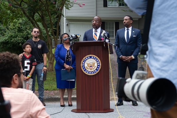 U.S. Sen. Raphael Warnock (at lectern) and Atlanta Mayor Andre Dickens (right) at a news conference on Monday in Atlanta's Adamsville neighborhood. (Ben Gray for the AJC)
