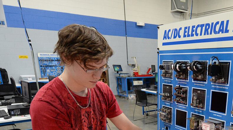 Alejandro Parker, 17, turns on a light bulb after completing a connection at the AC/DC electrical systems station at Georgia Northwestern Technical College.