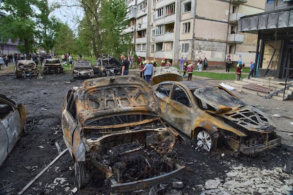 Municipal workers clean up burnt cars in the residential area following Russia's drone attack in Kyiv, Ukraine, Sunday, May 4, 2025. (AP Photo/Efrem Lukatsky)