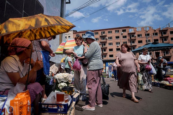 People shop at a street market near a building which was damaged by a Russian attack in Kyiv, Ukraine, on Thursday, July 10, 2025. (AP Photo/Evgeniy Maloletka)