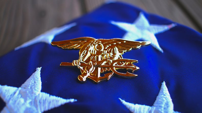 Navy SEAL trident rests atop a folded American flag