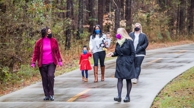 Blackwell film studio has traded land with DeKalb County making way for a new park with a splash pad, security, playgrounds and outdoor space for the Bouldercrest community. Neighborhood leaders, including Pat Culp, from left, the Clark family (Demi, 3; mother Alison, 7-month-old Lucas), Ingrid Buxbaum and Sarah Cotten, walk a path that will soon be part of the film studio Friday, Feb 12, 2021. A mile away, ground has been broken for the new DeKalb park. (Jenni Girtman for The Atlanta Journal-Constitution)