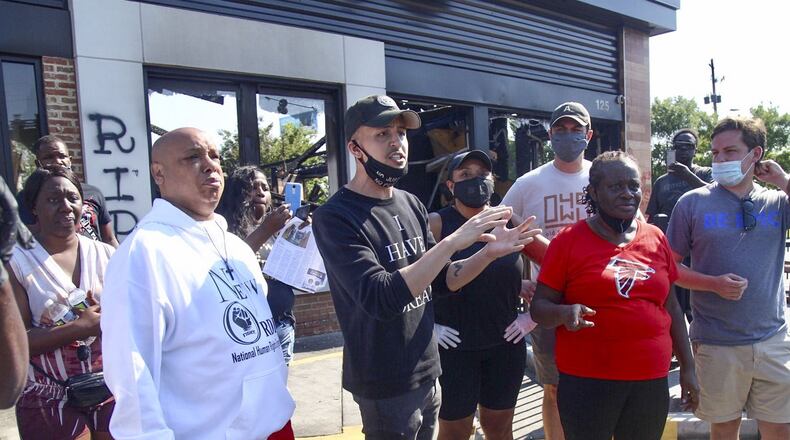 Atlanta councilman Antonio Brown introduced legislation that would ban police use of rubber bullets, stun grenades and military style vehicles. Here he (center) speaks to residents Sunday at the Wendy’s where Rayshard Brooks, a 27-year-old Black man, was shot and killed by Atlanta police Friday evening during a struggle in a Wendy’s drive-thru line. Steve Schaefer for the Atlanta Journal Constitution