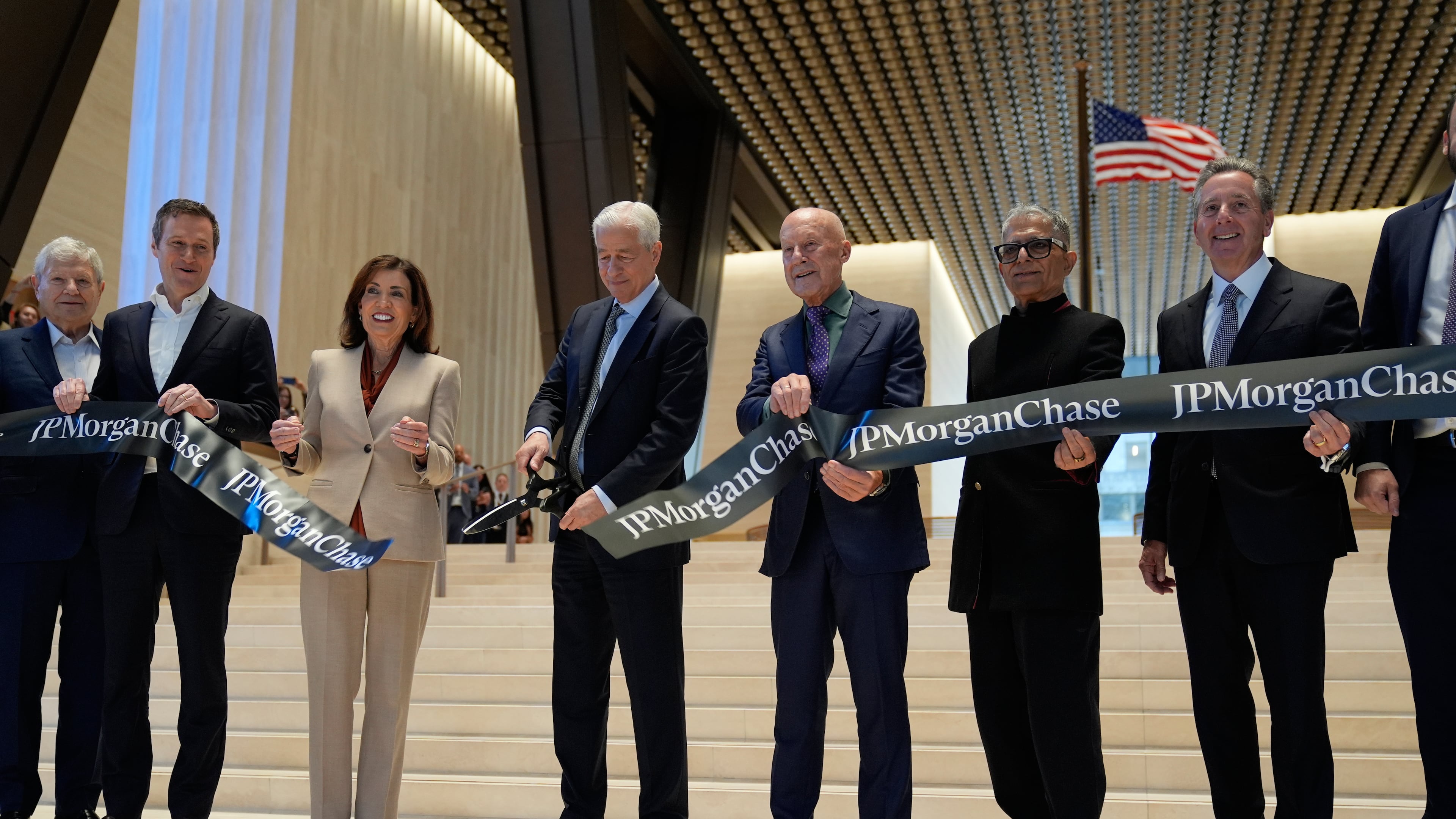 JPMorgan Chase CEO Jamie Dimon, fourth from left, cuts the ribbon on a new JPMorgan Chase building during a ceremony in New York, Tuesday, Oct. 21, 2025. Also holding the ribbon, from left to right: Jerry Speyer, Rob Speyer, NY Governor Kathy Hochul, Dimon, Norman Foster, Deepak Chopra and David Arena. (AP Photo/Seth Wenig)