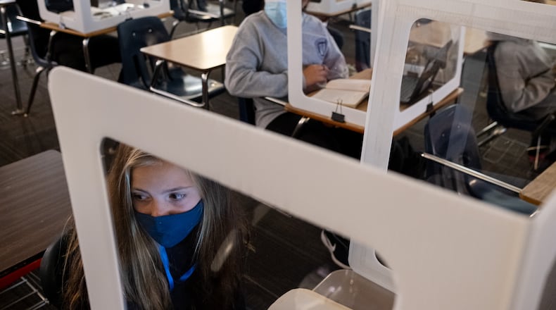 Celeste Martin (left) and Monserrath Guerrero look to their teacher from behind plastic partitions during their language arts class at Marietta Middle School on Thursday afternoon, Nov. 5, 2020. Even though there are only five students in the room during class, they all wear masks and sit behind plastic partitions. (Ben Gray for The Atlanta Journal-Constitution)