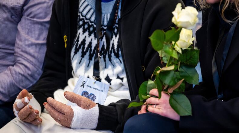 A victim with burned hands and relatives attend the official commemorative ceremony for the victims of the deadly fire at the "Le Constellation" bar in Crans-Montana, in Martigny, Switzerland, Friday, Jan. 9, 2026. (Laurent Gillieron/Keystone/Pool via AP)