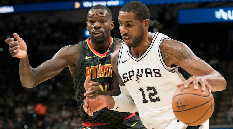 San Antonio Spurs forward LaMarcus Aldridge (12) drives around Atlanta Hawks center Dewayne Dedmon during the first half of an NBA basketball game, Monday, Nov. 20, 2017, in San Antonio. (AP Photo/Darren Abate)