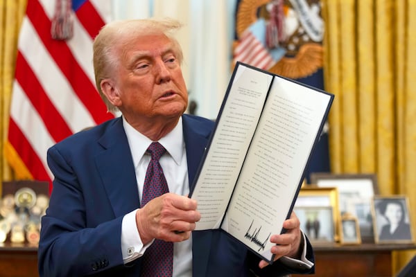 FILE - President Donald Trump holds up a signed executive order aiming to declassify remaining federal records relating to the assassinations of President John F. Kennedy, Sen. Robert F. Kennedy, and Martin Luther King Jr., in the Oval Office of the White House, Jan. 23, 2025, in Washington. (AP Photo/Ben Curtis, File)