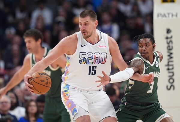 Denver Nuggets center Nikola Jokic, left, collects the ball as Milwaukee Bucks guard Kevin Porter Jr. defends in the first half of an NBA basketball game Wednesday, March 26, 2025, in Denver. (AP Photo/David Zalubowski)