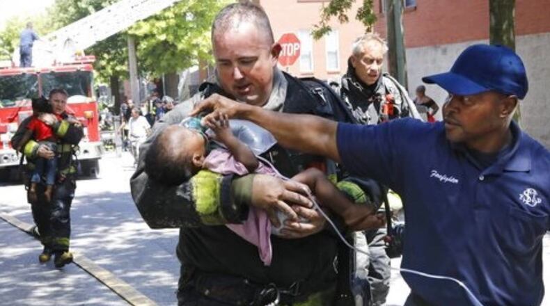 St. Louis firefighter Patrick Ferguson carries one of the injured babies as fellow firefighter Mike Perkins applies oxygen Thursday afternoon.