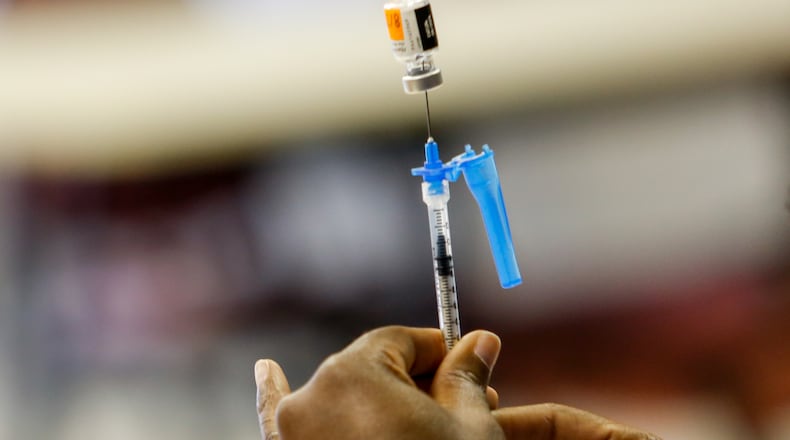 Preparing to administer a Pfizer vaccination, a CORE nurse works to dilute and divide the medication before a 12-year-old receives her first shot at The Nett Church in Lilburn in 2021.  Jenni Girtman for The Atlanta Journal-Constitution