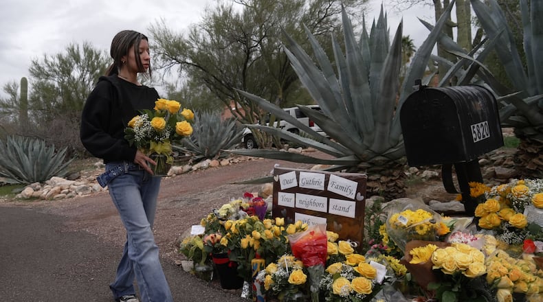 A person places flowers in front of Nancy Guthrie’s home in Tucson, Ariz., on Friday, Feb. 13, 2026. (AP Photo/Ty ONeil)